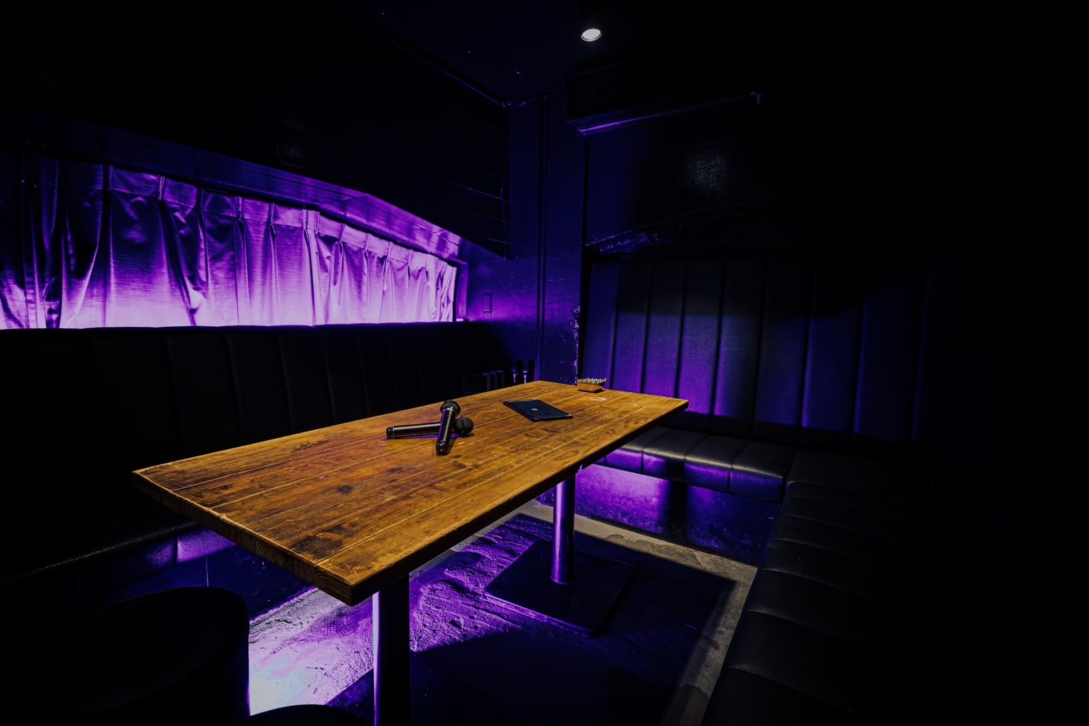 XO Bar カラオケ個室 - 木製テーブルとソファ席、紫のアンビエント照明